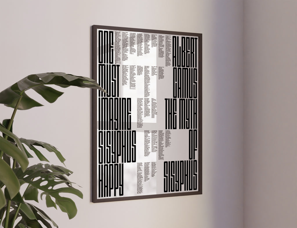The myth of sisyphus poster with a black and white abstract geometric design featuring text-like blocks, hanging on a light gray wall next to a green plant.