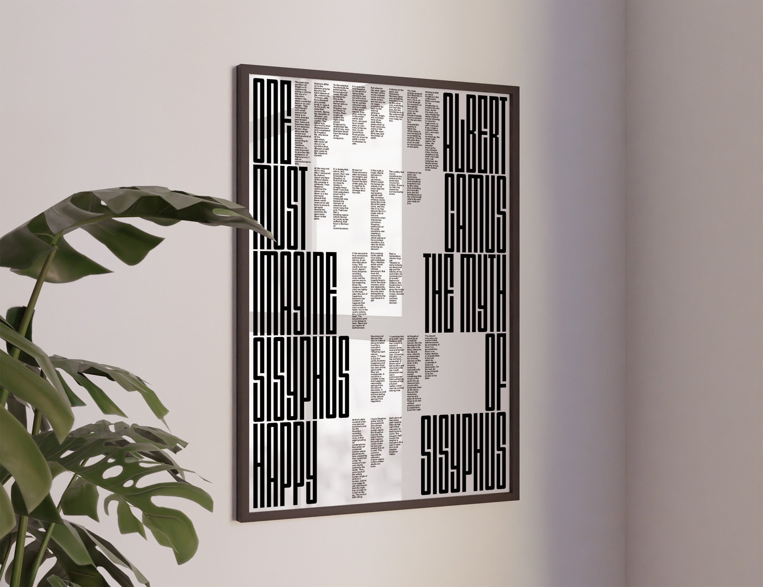 The myth of sisyphus poster with a black and white abstract geometric design featuring text-like blocks, hanging on a light gray wall next to a green plant.